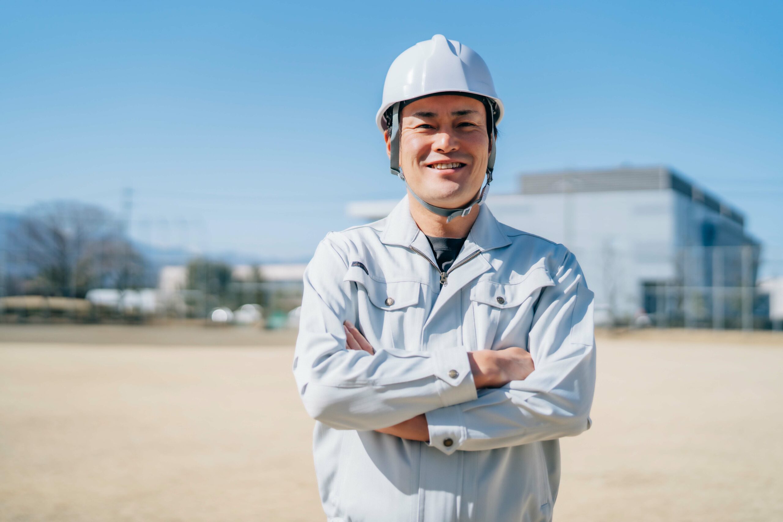 ヘルメットを腕を組んでにこやかに笑う若い男性職人